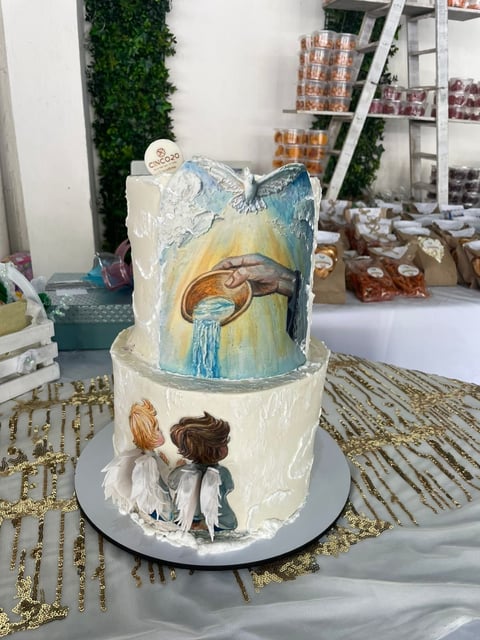 Two-tiered decorative cake with painted figures of two children looking at an eye-like design on top tier, displayed on a gold beaded mat